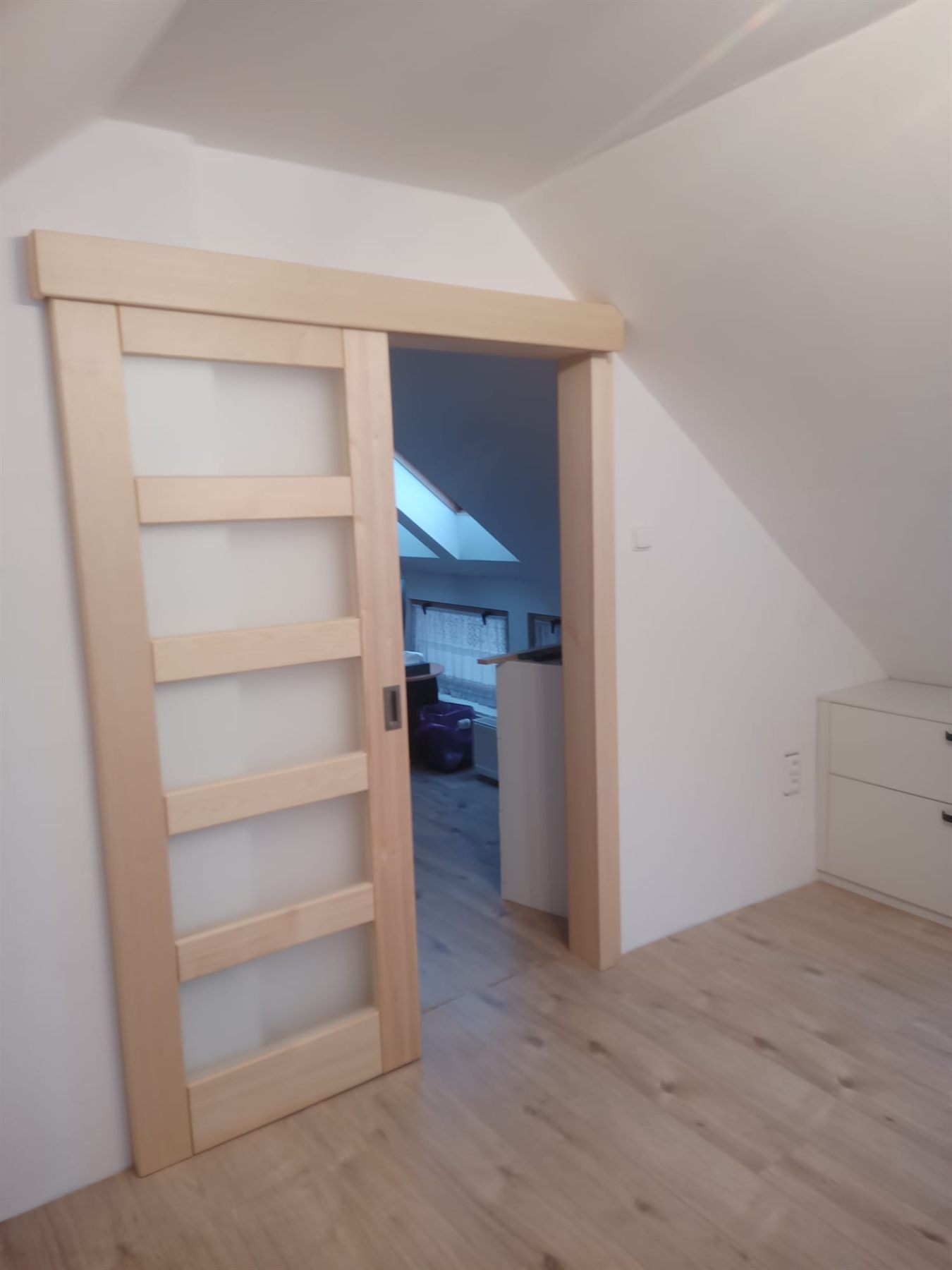 Posuvné dveře s prosklením jedoucí po stěně v podkroví