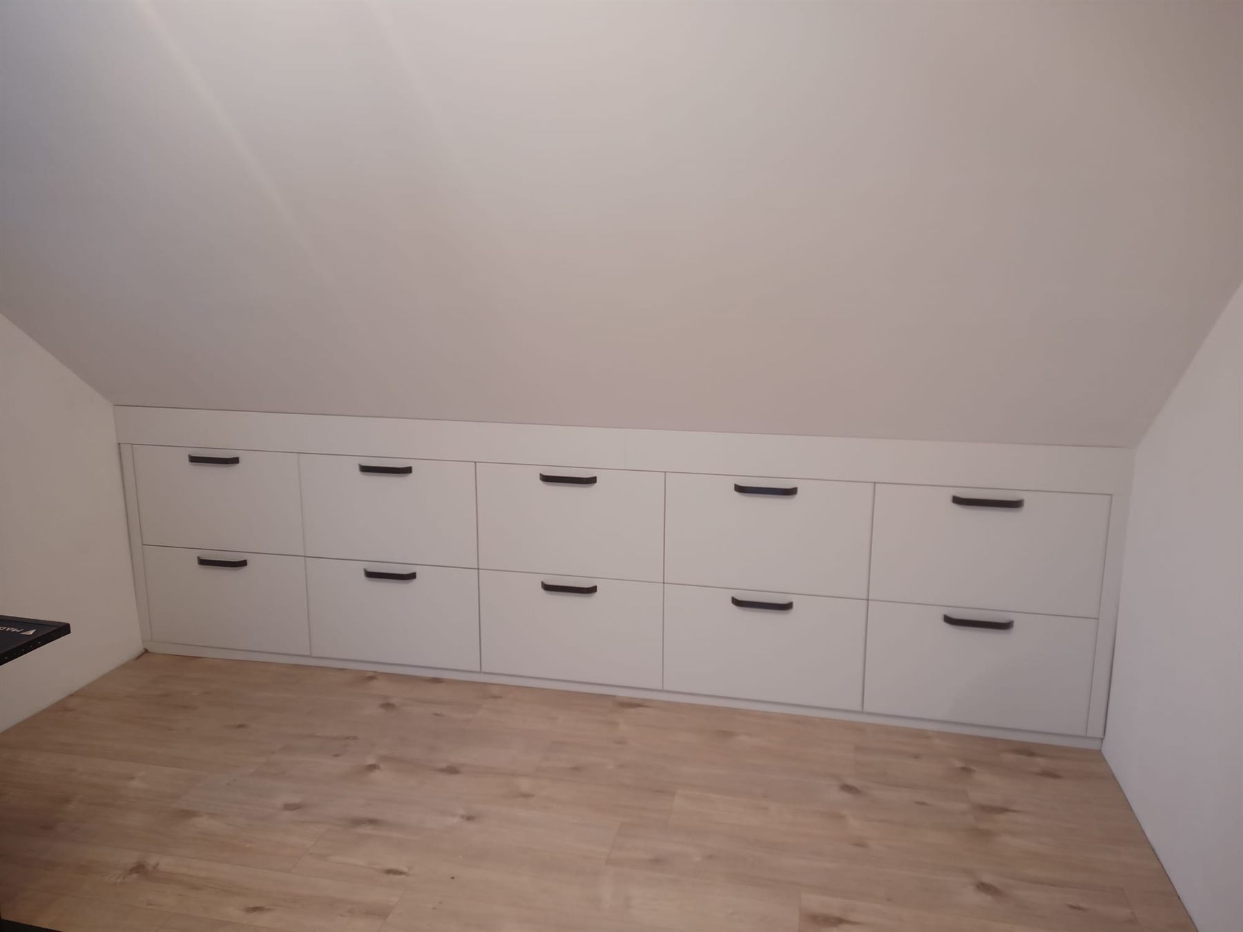 Řada vestavěných zásuvek pod šikmou stěnou podkroví